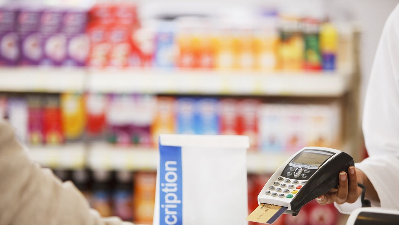 Pharmacist holding credit card payment device for customer.