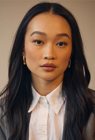 Actor and star of the suspense thriller Presence Callina Liang wearing a gray blazer paired with a cropped white button-down shirt, a dark gray miniskirt, and black Prada loafers with white socks.