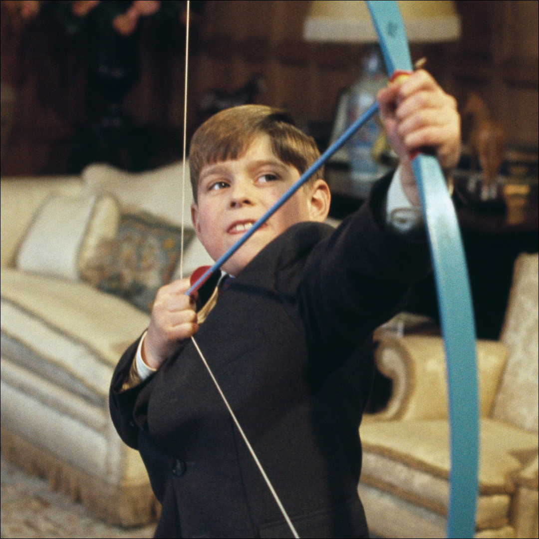 Ex-Prince Andrew as a child fires a bow and arrow inside Windsor Castle in 1969