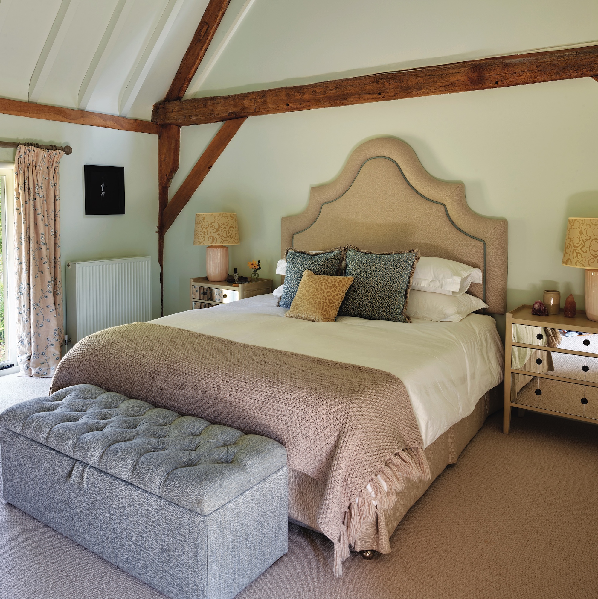 bedroom with upholstered cream headboard and pale blue blanket box at bottom of bed