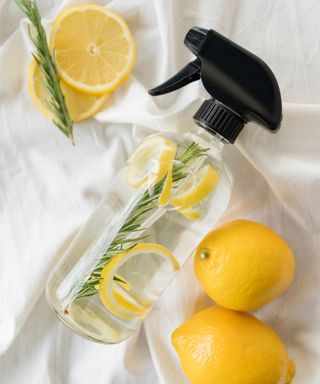 A glass bottle of lemon room spray with lemons around it