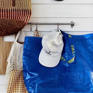 white wall with hanging hook and blue bag and a white cap