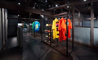 Grey walls and dark wood features with brightly-coloured clothing hanging on rails