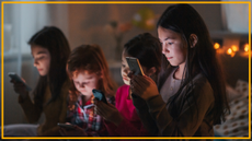 Four children look at their phones in a bedroom