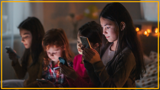 Four children look at their phones in a bedroom