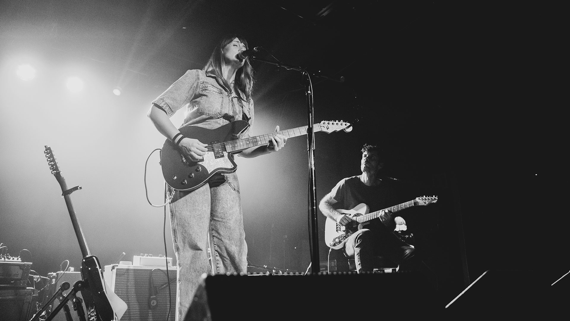 Black and white image of Jenn Wasner performing onstage with her Reverend electric guitar