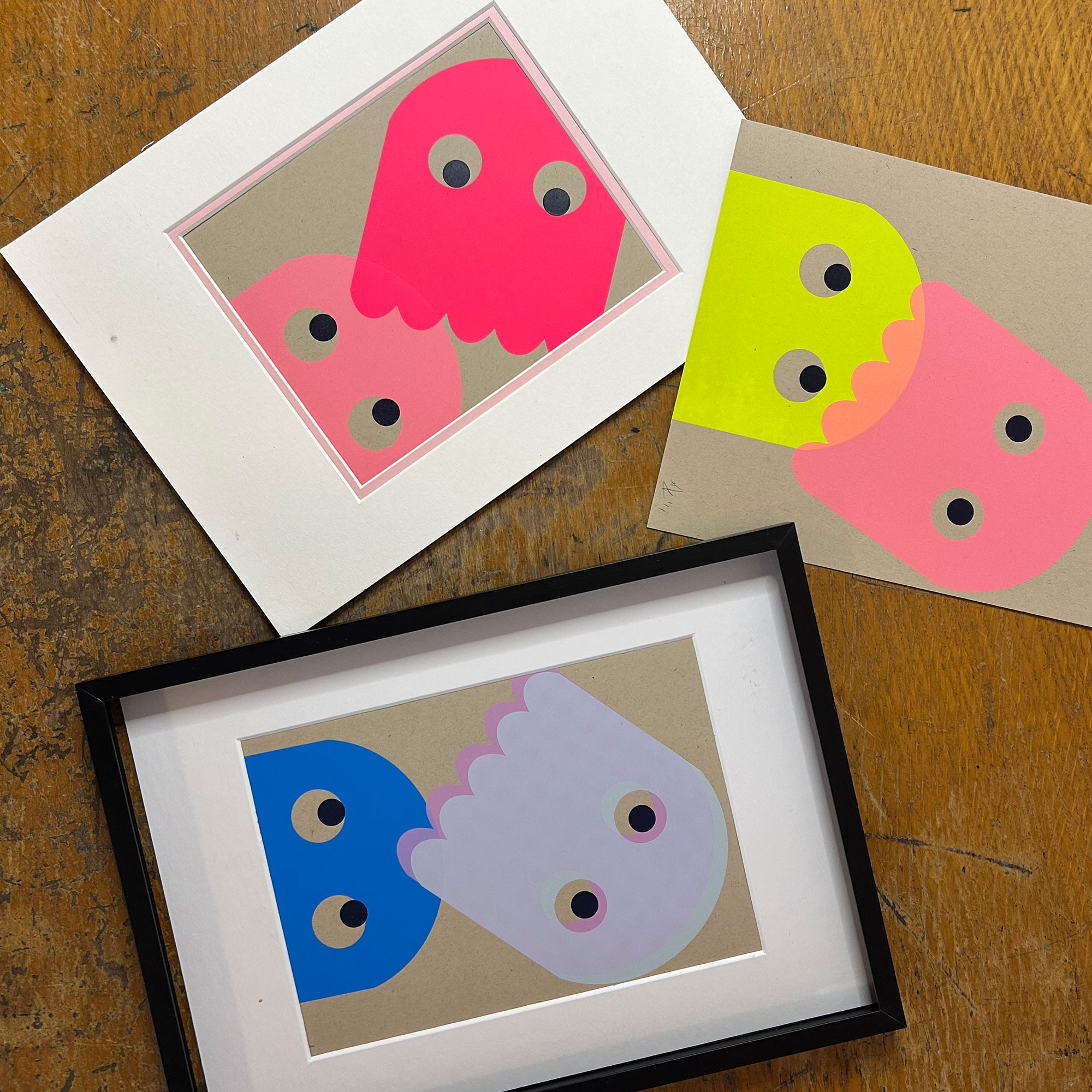 Three paintings of Pac-Man style ghosts in neon colours