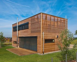 an exterior of a modular home by baufritz with wood cladding and outdoor terrace - www.baufritz.uk