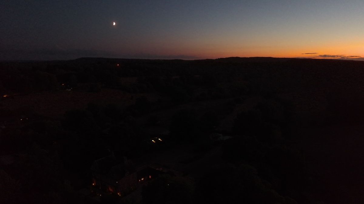 An aerial view of the UK countryside at last light - the moon is out, the sun is setting