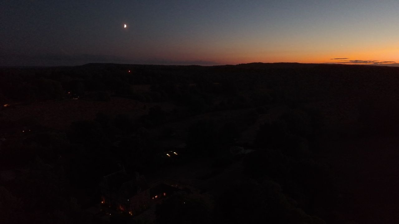 An aerial view of the UK countryside at last light - the moon is out, the sun is setting