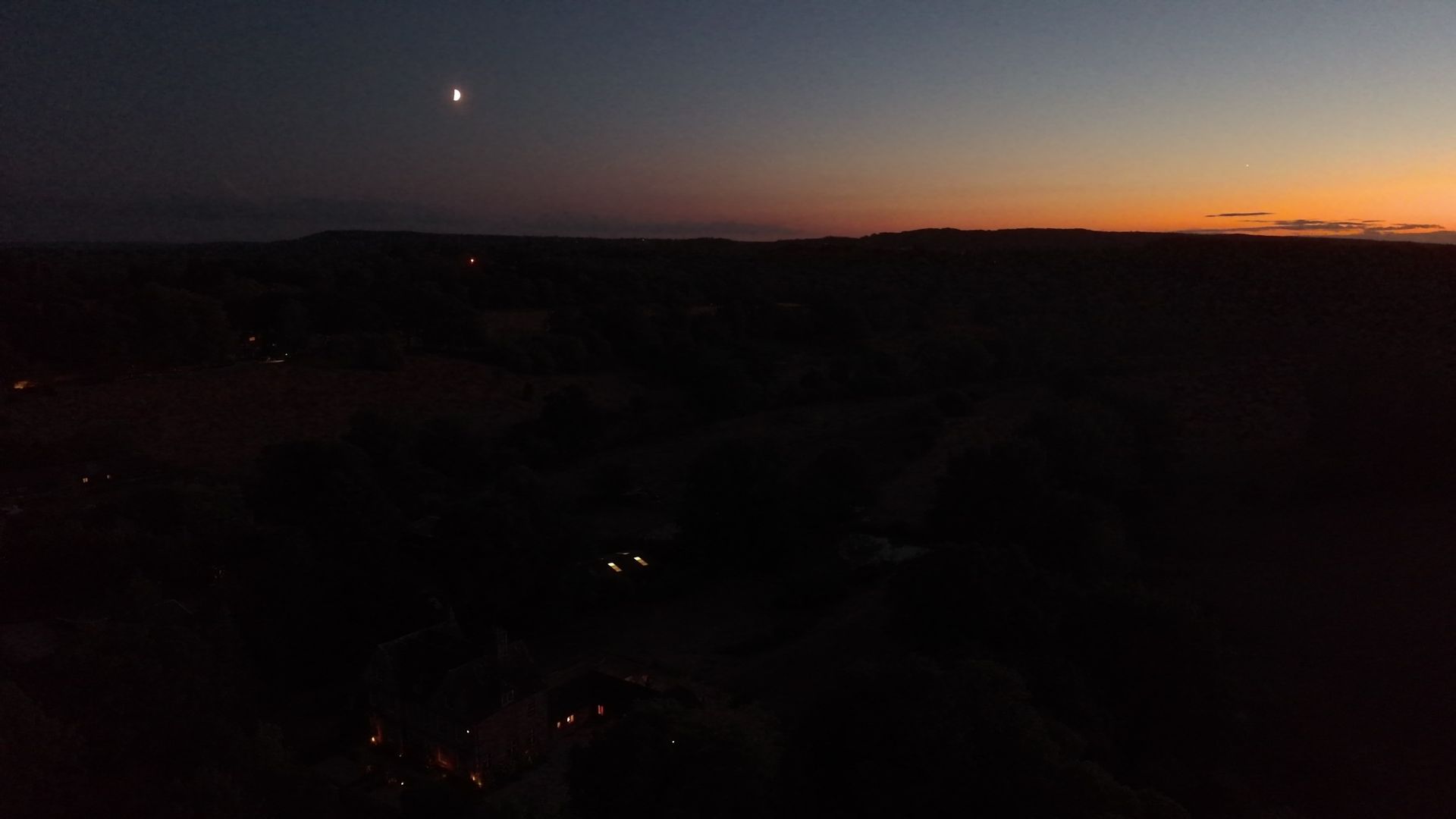An aerial view of the UK countryside at last light - the moon is out, the sun is setting