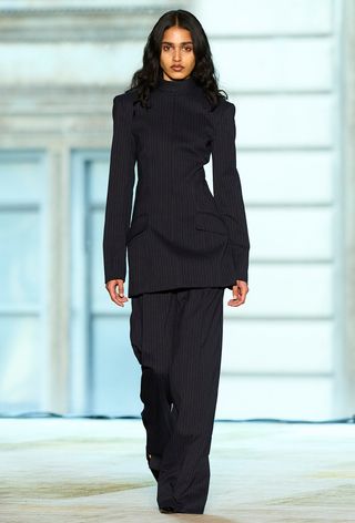 the navy color trend shown on Aknvas's fall runway worn by a model wearing a navy pinstripe blazer top with matching trousers and black shoes