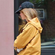 Jennifer Lawrence in NYC wearing a yellow windbreaker, red pants, boat shoes, and a black baseball cap