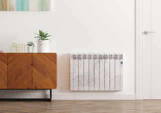 Marble effect electric radiator on white wall next to sideboard