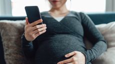 A pregnant woman looks are her phone