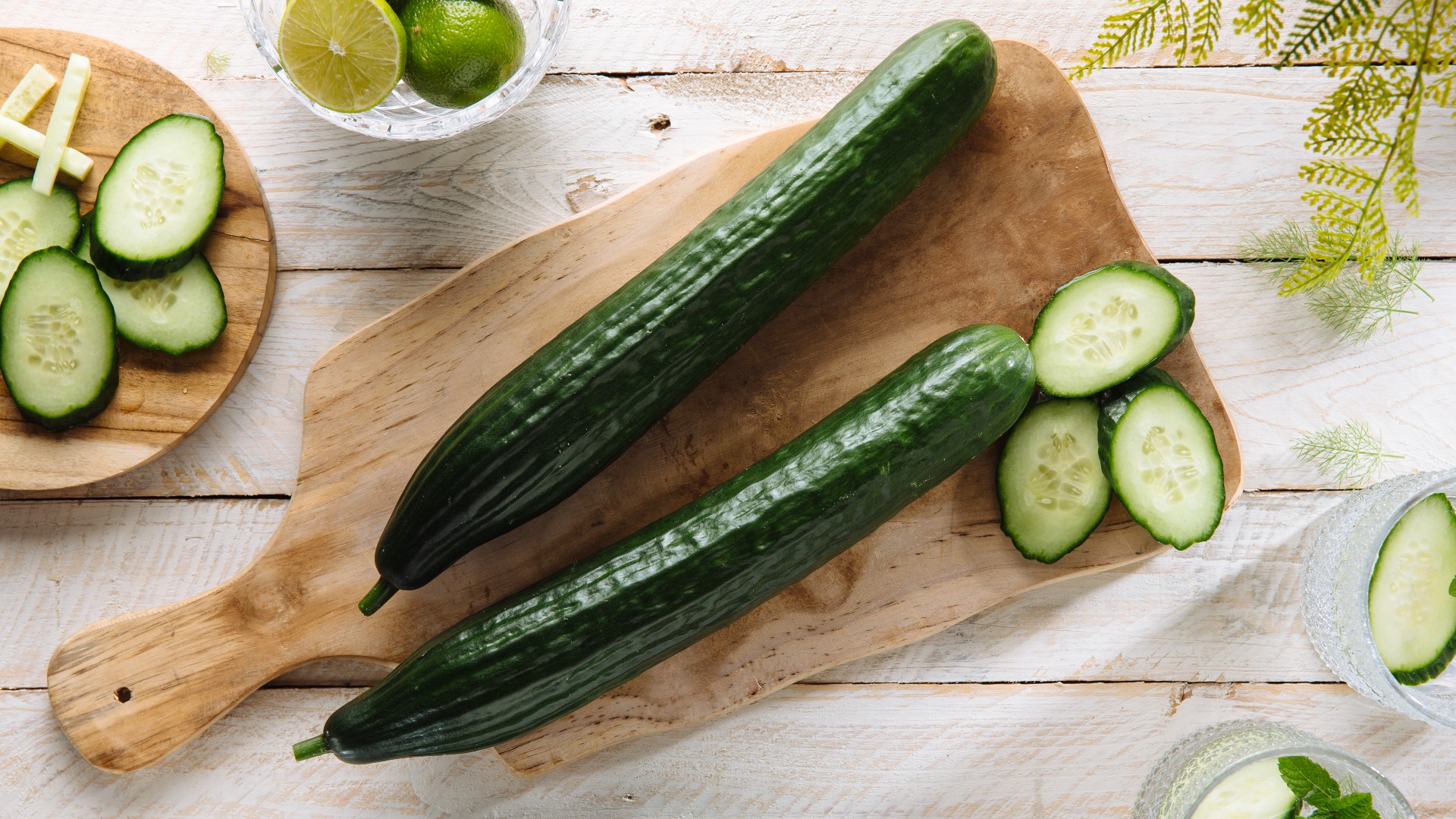Whole and sliced cucumber on chopping board