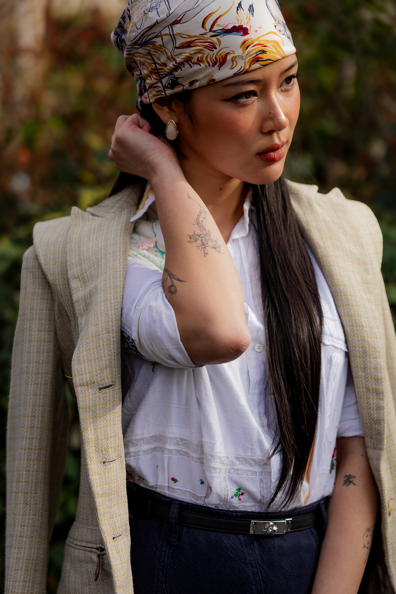 A woman wearing a silk scarf bandana on her head at Paris Fashion Week AW26