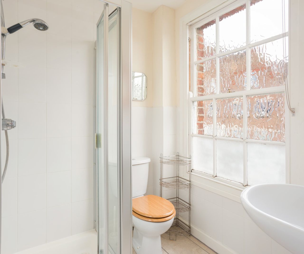 A white bathroom with a walk in shower and a wooden toilet
