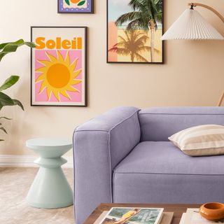 A living room with a lilac sofa and art prints on the wall