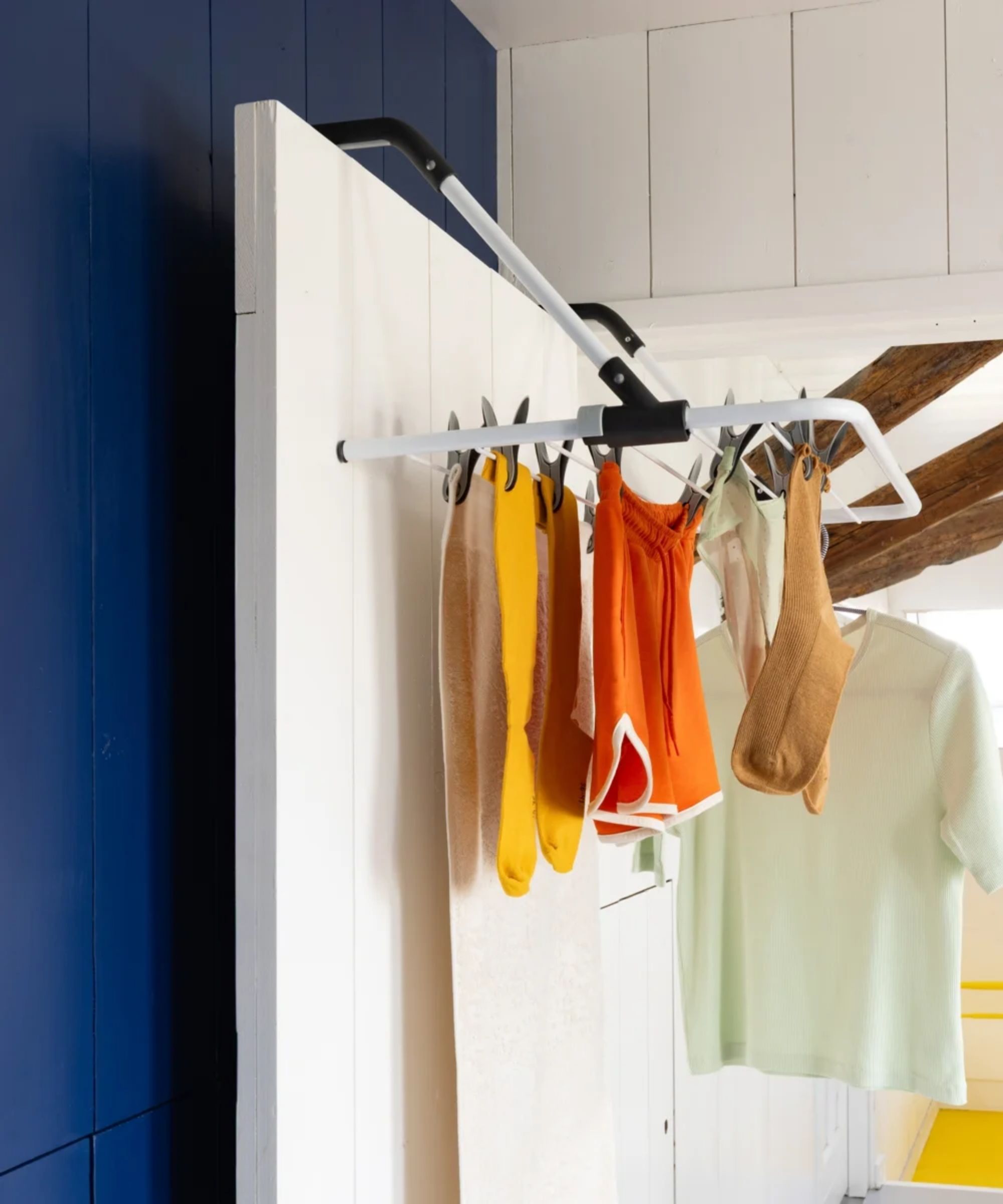 Over-door drying rack hanging on a white door with a navy blue panelled wall behind