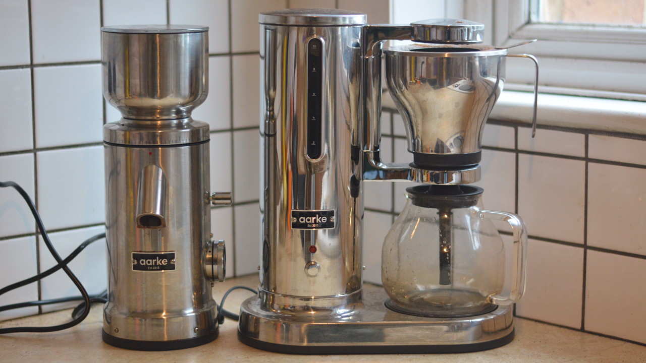 Image of the Aarke Coffee System &ndash; a stainless steel coffee bean grinder and drip coffee maker &ndash; positioned on a kitchen counter