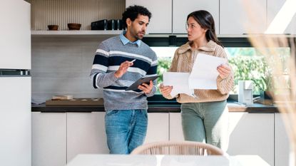 A man and a woman discuss finances in their kitchen