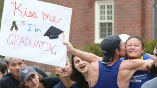 A Boston Marathon runner kisses a young woman on the cheek outside Wellesley College. The woman is holding a sign which reads “kiss me I'm graduating”