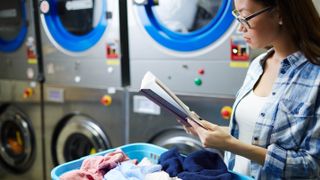 Student looking at book while doing laundry