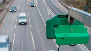 An automated number-plate recognition (ANPR) camera watches over a dual carriageway