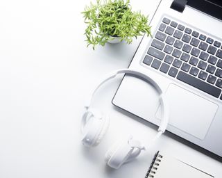 White headphones on white desk with laptop