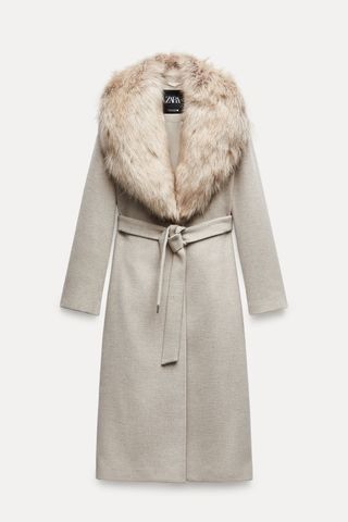 a gray zara coat with a faux fur collar and wrap belt in front of a plain backdrop