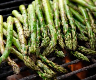 A close up of asparagus nearly finished cooking on a charcoal grill