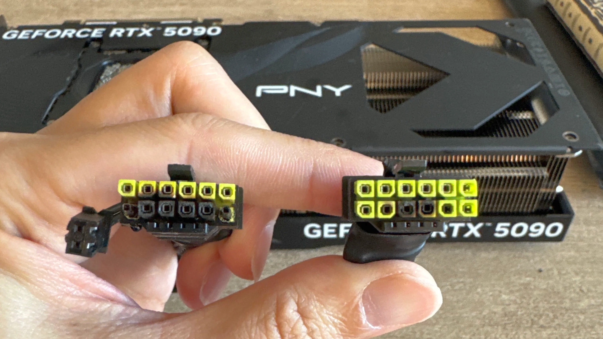 A photograph of a GeForce RTX 5090 card and the 12V-2x6 cable it burned on both ends.