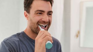 man brushing teeth with electric toothbrush