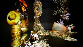 Immersive experience; a woman performs yoga in a room of art