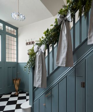 hallway with blue staircase with Christmas wreath with large blue striped bows