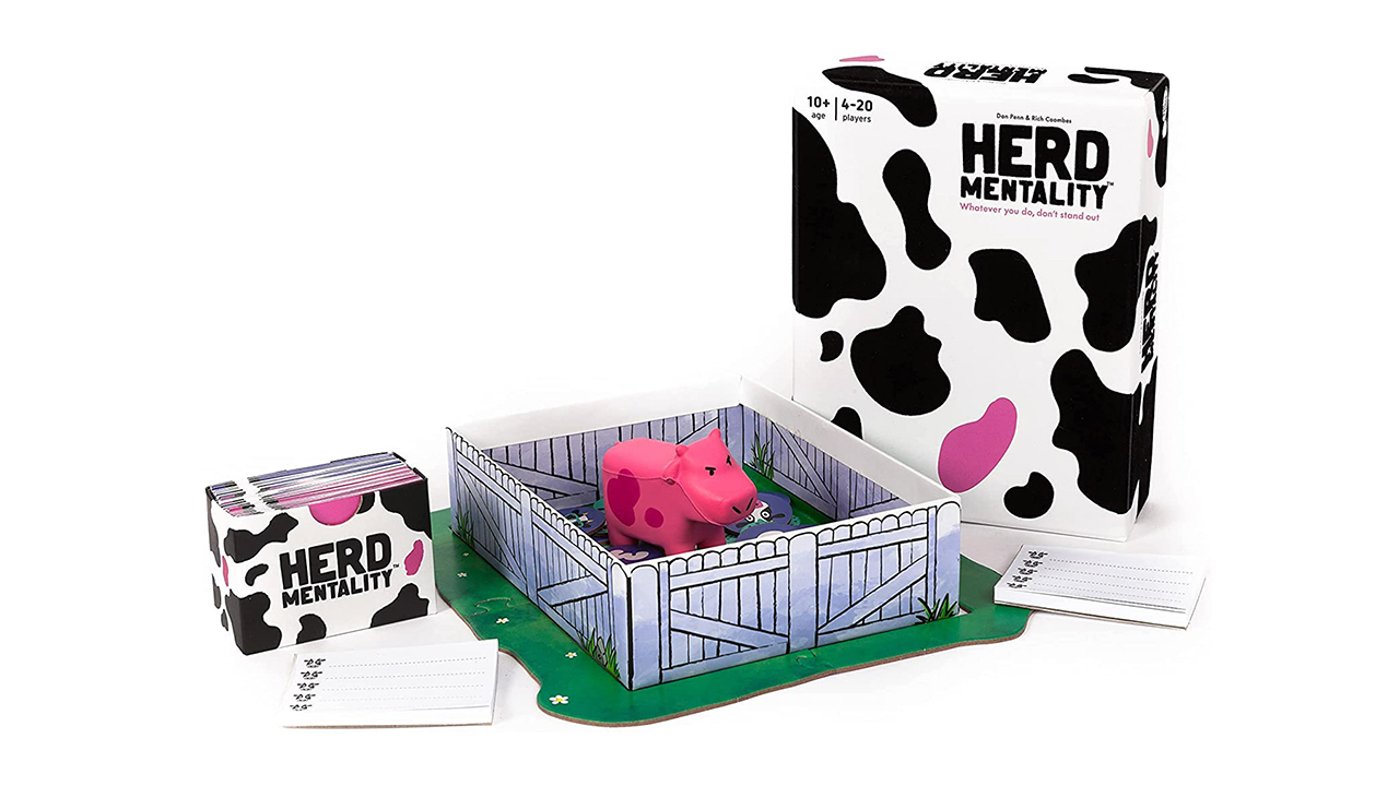 A stack of Herd Mentality cards next to a soft toy cow