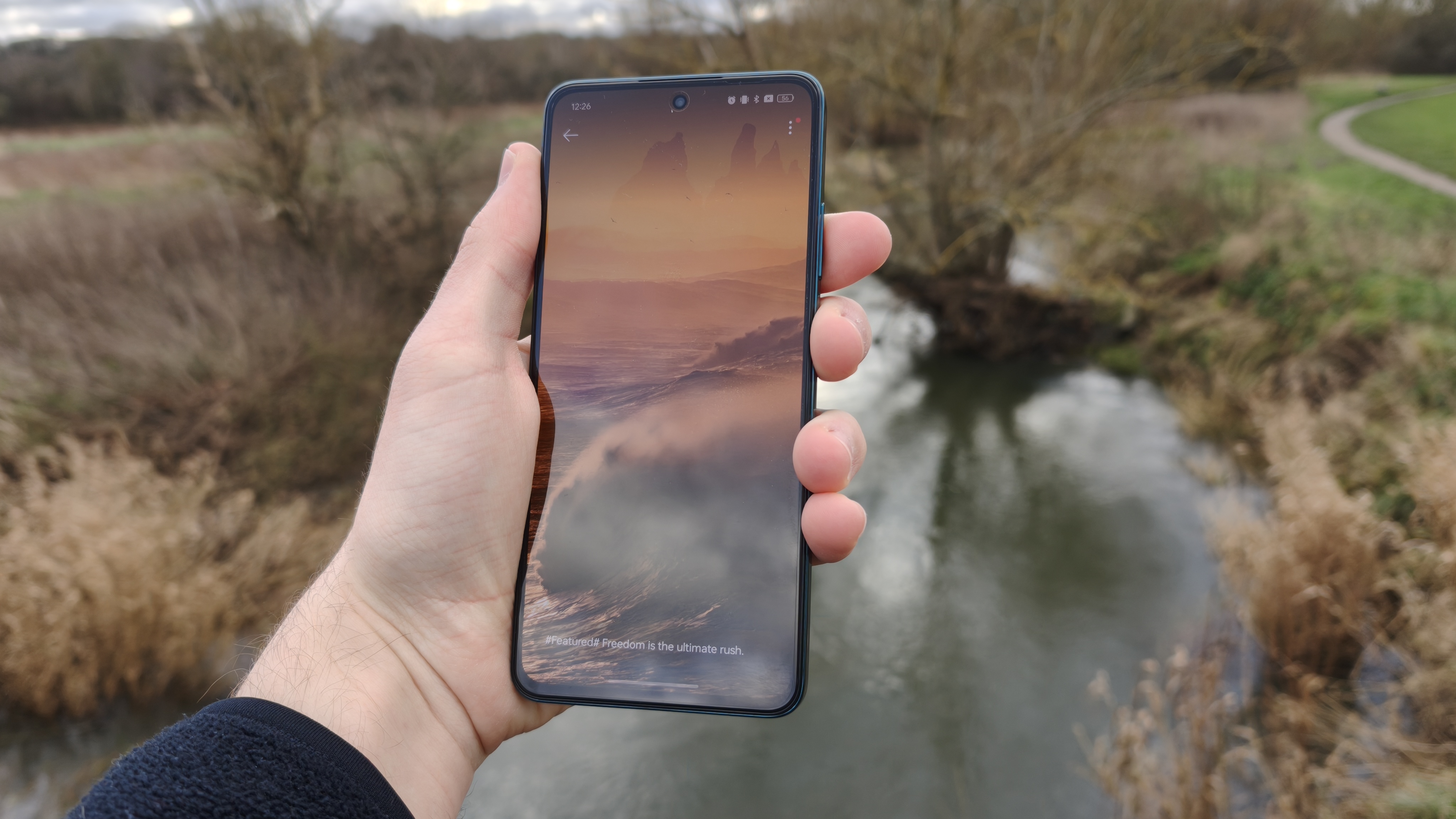 The Oppo Reno 12 FS 5G displaying its magazine unlock against a river