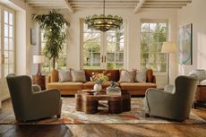 a living room in a light airy space with a sofa, two armchairs, coffee table, and green glass chandelier