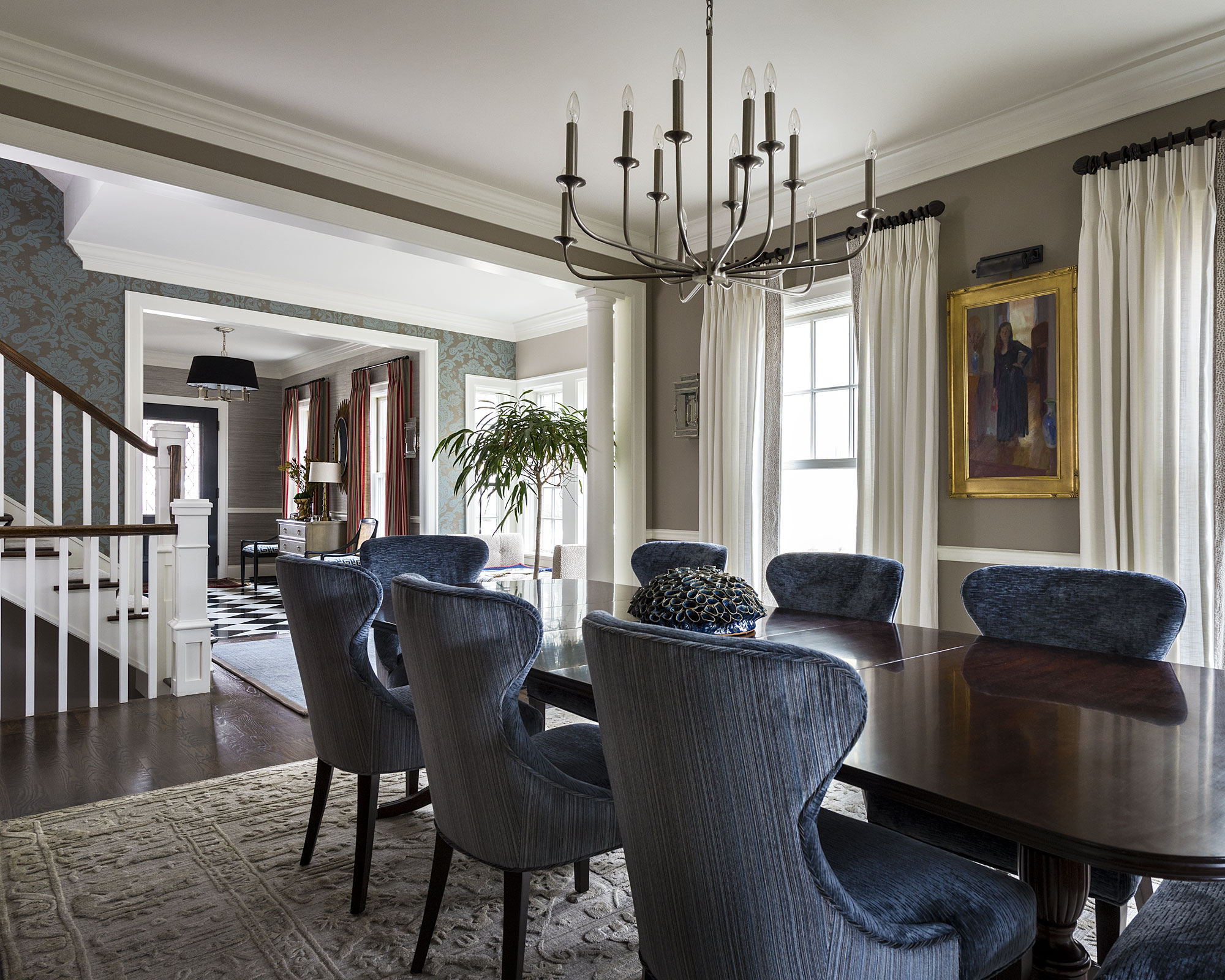 A dining room with a long table with blue wingback chairs