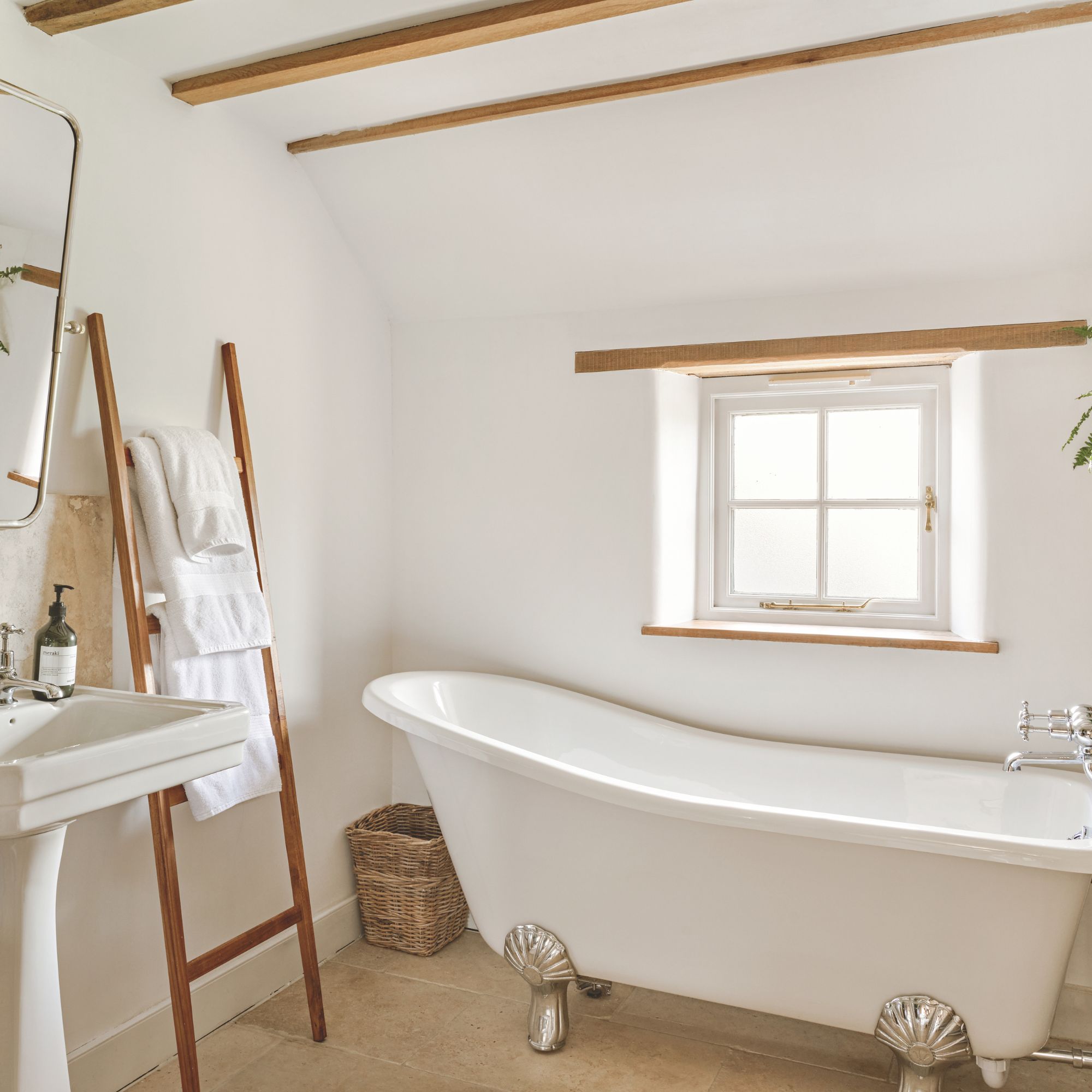 Cottage bathroom with wooden ceiling beams, freestanding bath tub and wooden towel rail