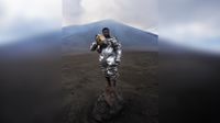 Phillip, a self-taught volcanologist, stands barefoot atop a volcanic rock bomb. Wearing a lava-protection suit, the volcano smoulders behind him, sending a plume of gas and sulphur into the sky