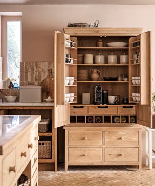 A large wooden kitchen pantry filled with rustic storage containers
