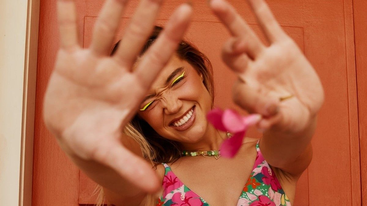 model wearing a floral bathing suit and holding up a flower