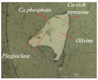 A sample of the Itokawa asteroid brought back to Earth by the Hayabusa spacecraft. The phosphate minerals marked in the image helped scientists better understand the asteroid's history.