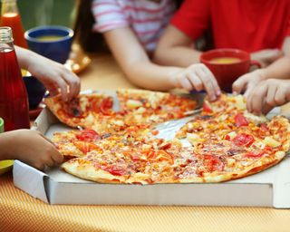 children eating pizza served in a pizza box