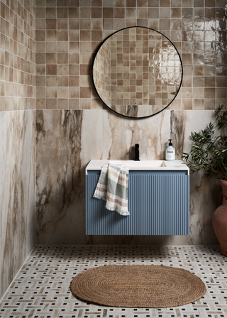 A light brown bathroom with blue fluted vanity unit and patterned brown flooring