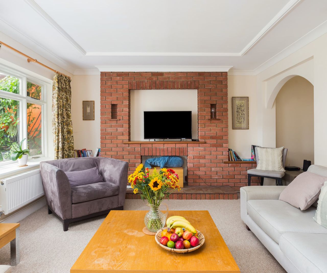 A living room with a brick wall and a white carpet, walls and roof