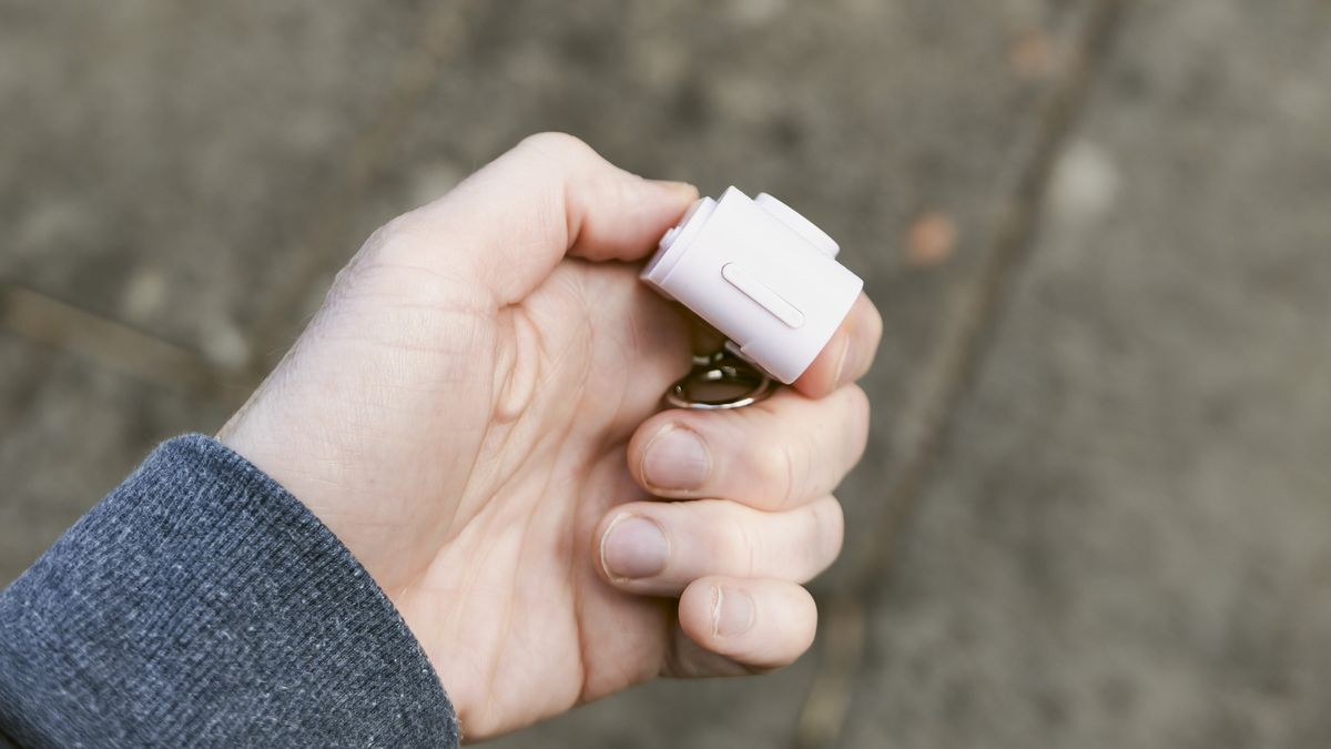 Miniature pink keychain camera, the 'Photo Creator Mini Digital Camera series 3', in user's hand, its side