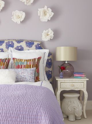 A bedroom with lavender wall paint, and bedding